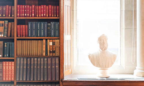 A bust in front of rows of different coloured books